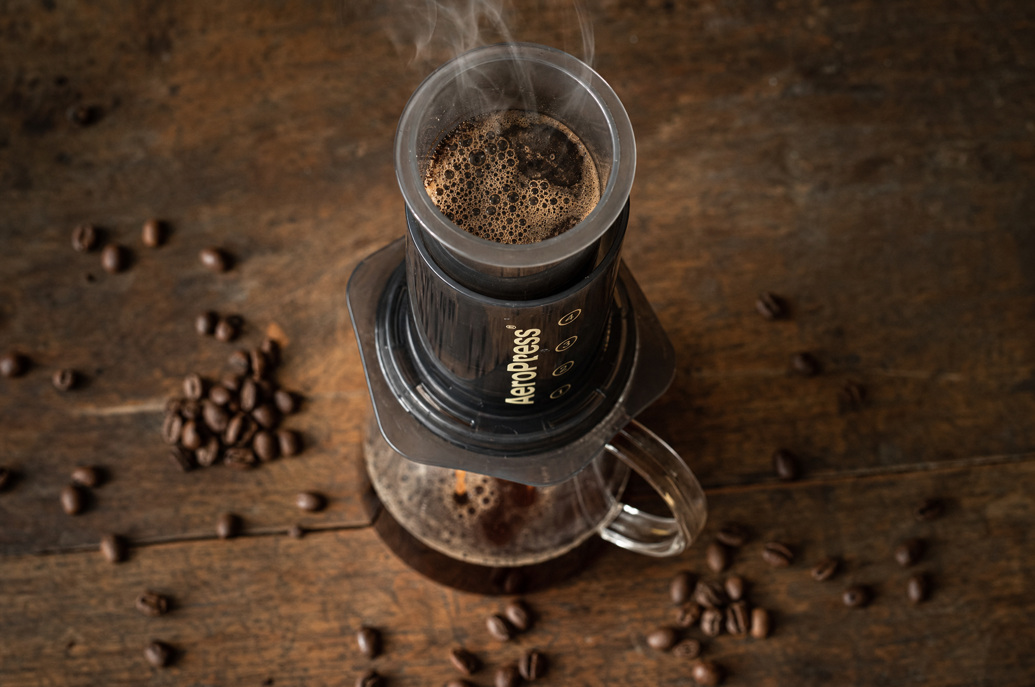 AeroPress coffee brewer pressing coffee into a glass carafe